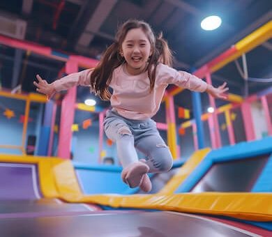 Happy young girl jumping high in the air at an indoor trampoline park arena.