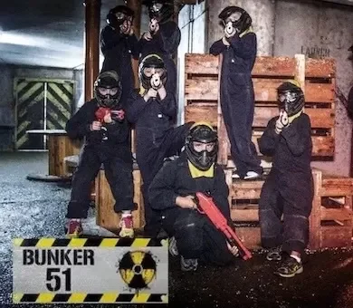 Group of kids wearing jumpsuits and holding laser guns inside the Bunker 51 nuclear bunker arena.
