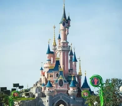 The beautiful pink Sleeping Beauty castle at Disneyland Paris under a bright blue sky.