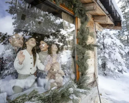 Family looking at snowy mountains from hotel window