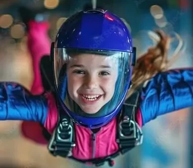 Smiling young girl experiencing zero gravity flight inside an indoor skydiving vertical wind tunnel.