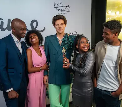 Family posing with life like celebrity wax figures at Madame Tussauds.