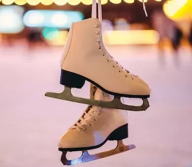 A pair of classic white ice skates hanging up with a blurred indoor bowling alley background.
